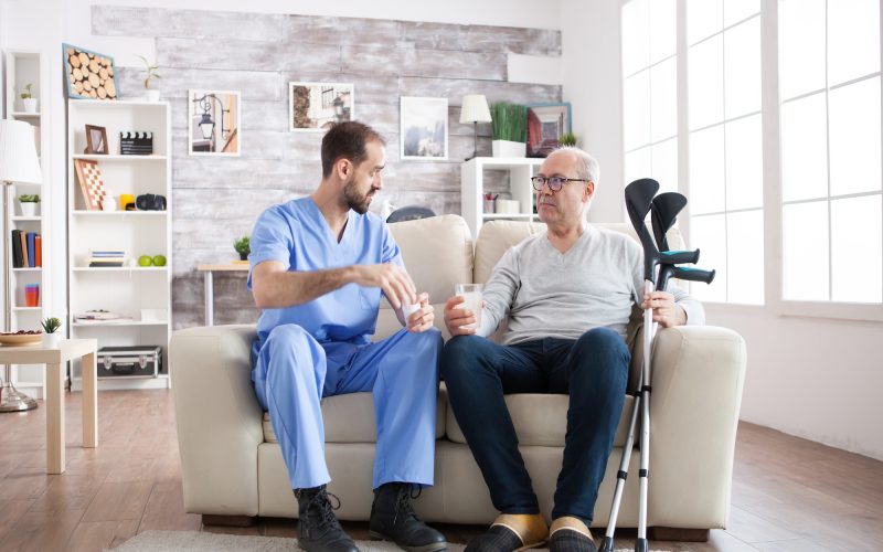 young-male-nurse-in-nursing-home-with-pills-for-senior-man.jpg